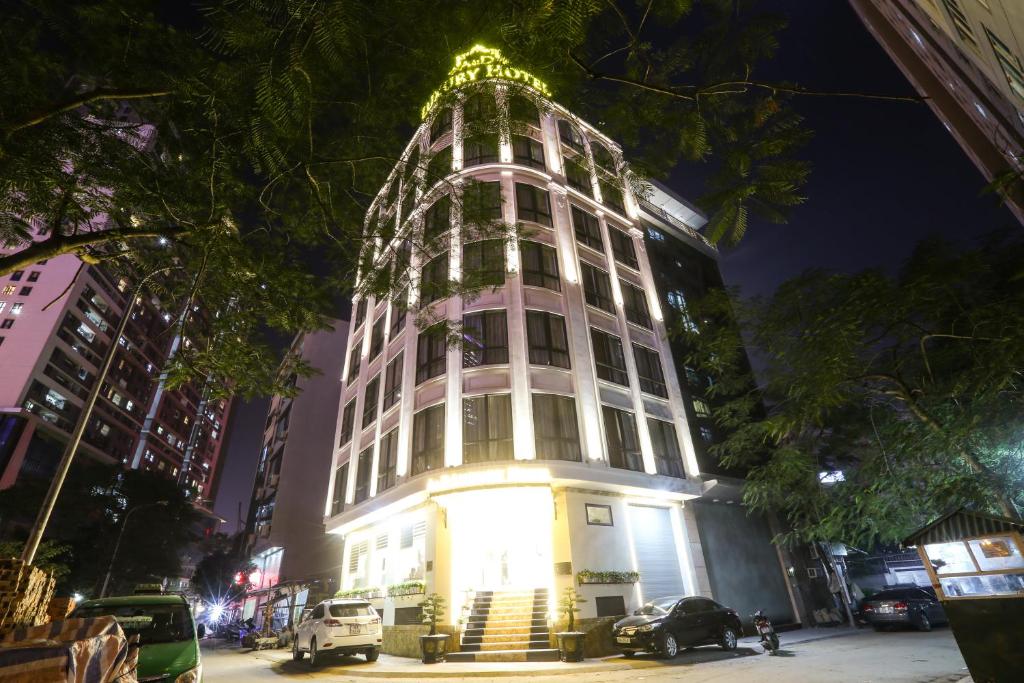 a tall white building with lights on top at night at A&D Luxury Hotel in Hanoi