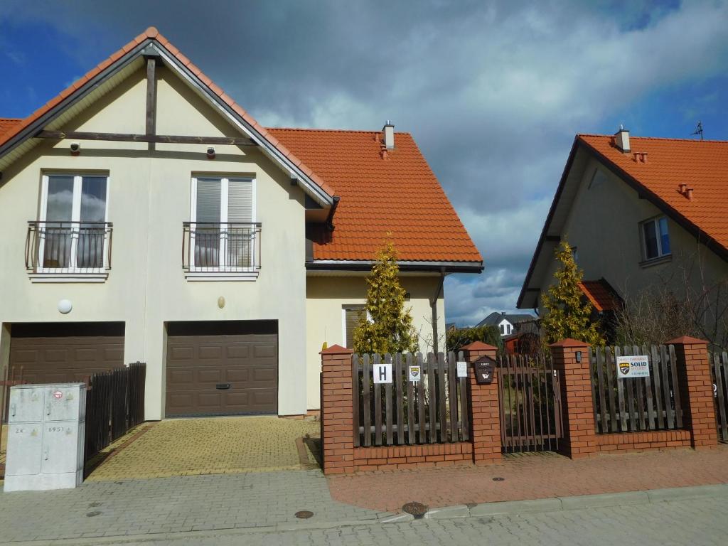 ein weißes Haus mit orangefarbenem Dach und einem Zaun in der Unterkunft Wynajem pokoi Białystok in Białystok