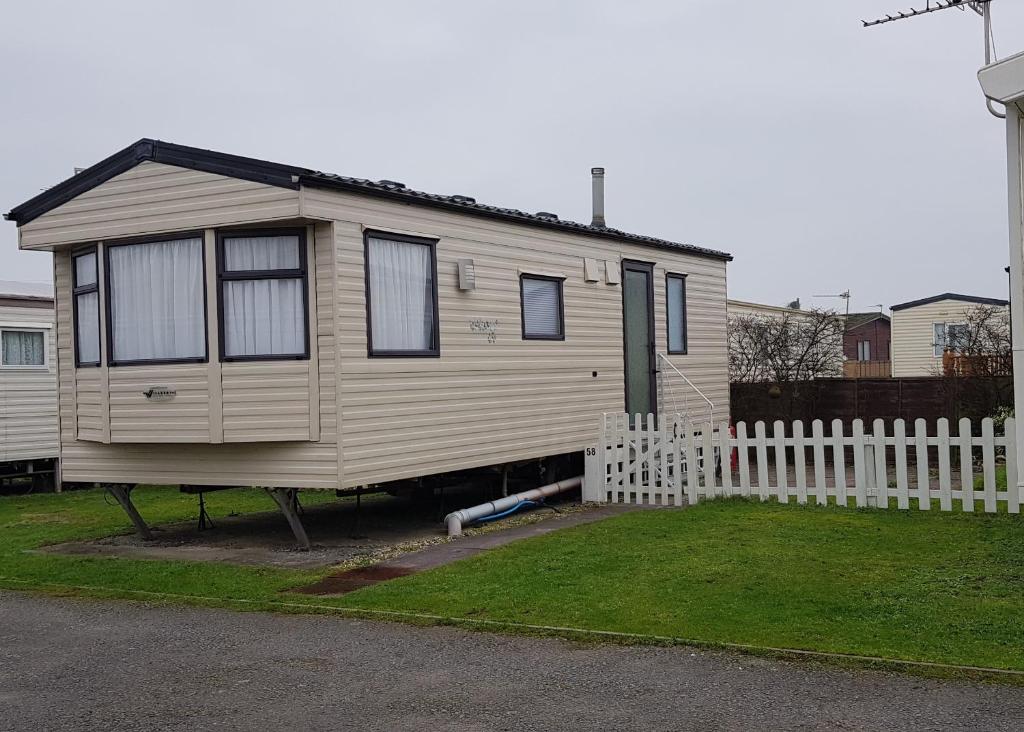 a tiny house in a yard next to a white fence at 4 Berth with private Garden - 58 Brightholme Holiday Park Brean! in Brean