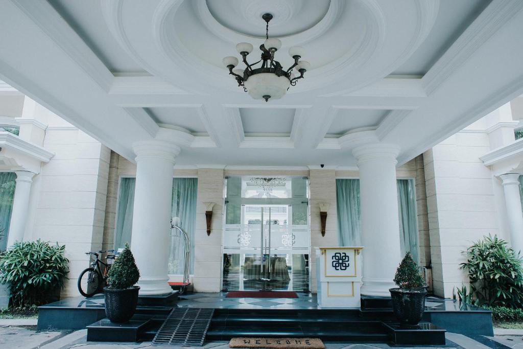 a white building with a ceiling with a chandelier at Adhiwangsa Hotel in Solo