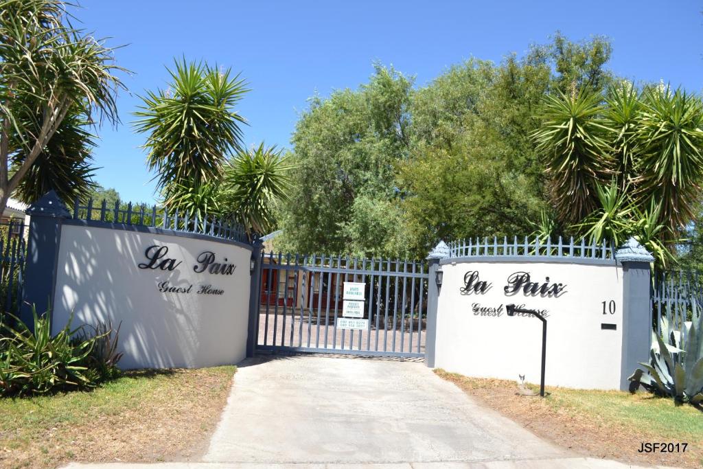 a gate at the entrance to a villa with palm trees at La Paix Guesthouse in Beaufort West