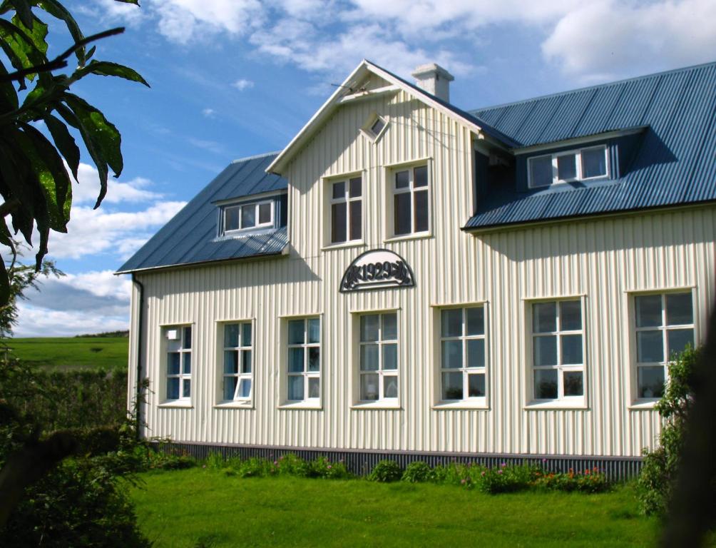 een wit huis met een blauw dak bij Guesthouse Húsid in Hlíðarendi