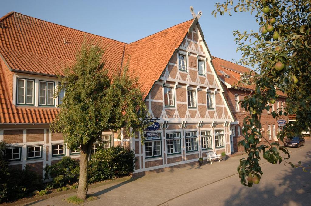 ein Gebäude mit einem orangenen Dach und einem Baum in der Unterkunft Hotel Altes Land in Jork