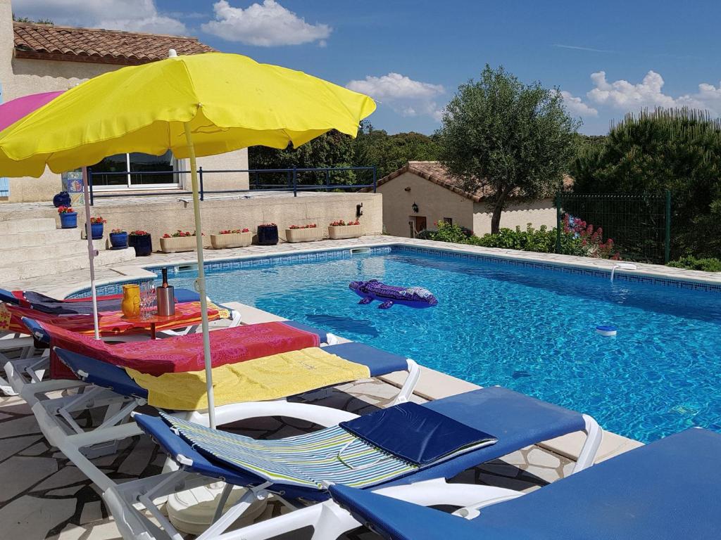 einen Pool mit Stühlen und Sonnenschirmen sowie einen Pool in der Unterkunft Stylish villa with private pool in Félines-Minervois