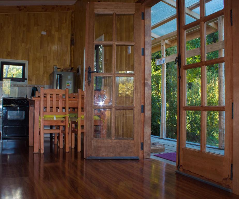 eine Küche und ein Esszimmer mit einem Tisch und einer Tür in der Unterkunft Rincón del Gaucho in Hornopiren