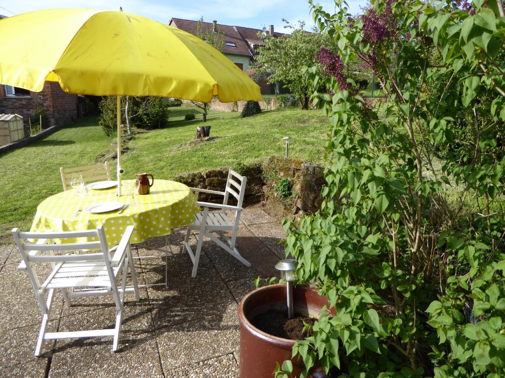 une table et des chaises jaunes sous un parapluie jaune dans l'établissement Les Rosiers, à Eschbourg