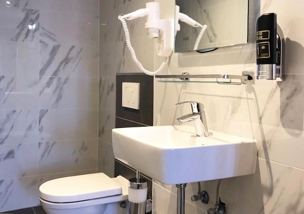 a white bathroom with a sink and a toilet at Facade Hotel Amsterdam in Amsterdam