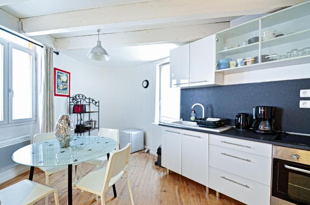 a kitchen with white cabinets and a table with chairs at Appartement du Palais Longchamps in Marseille