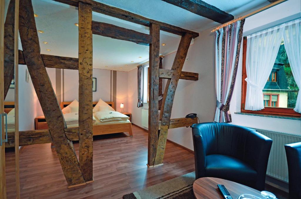 a room with a bedroom with a bed and a chair at Hotel Gästehaus auf der Lay in Beilstein