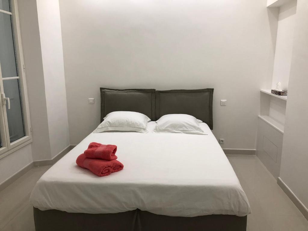 a white bed with a red towel on it at Magnifique Appartement Vue Mer in Vallauris