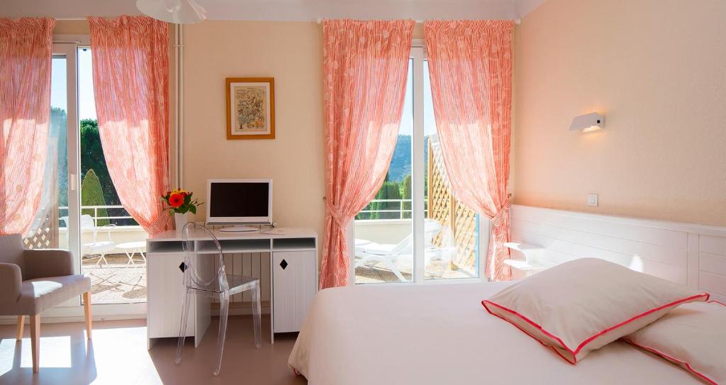 a bedroom with a bed and a desk and a window at Le Verdon in Gréoux-les-Bains