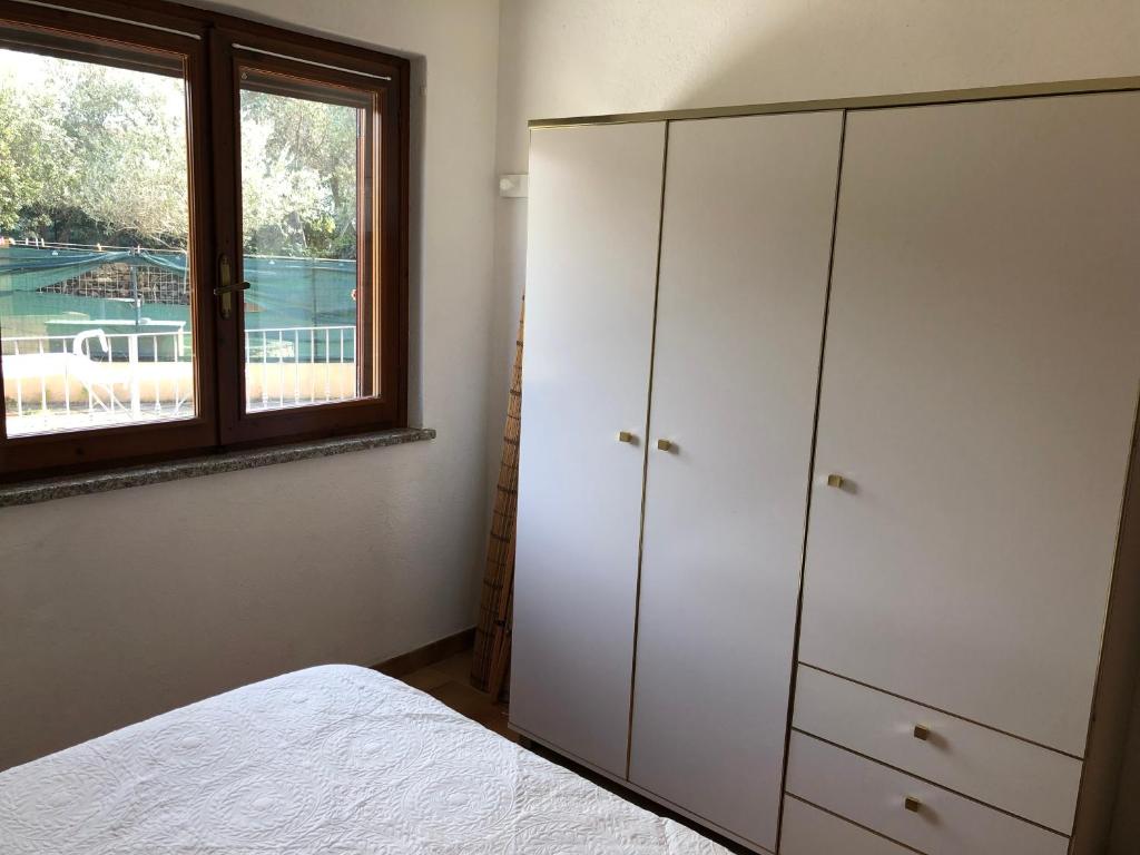 a bedroom with white cabinets and a window at Trilocale climatizzato con cortile in San Teodoro