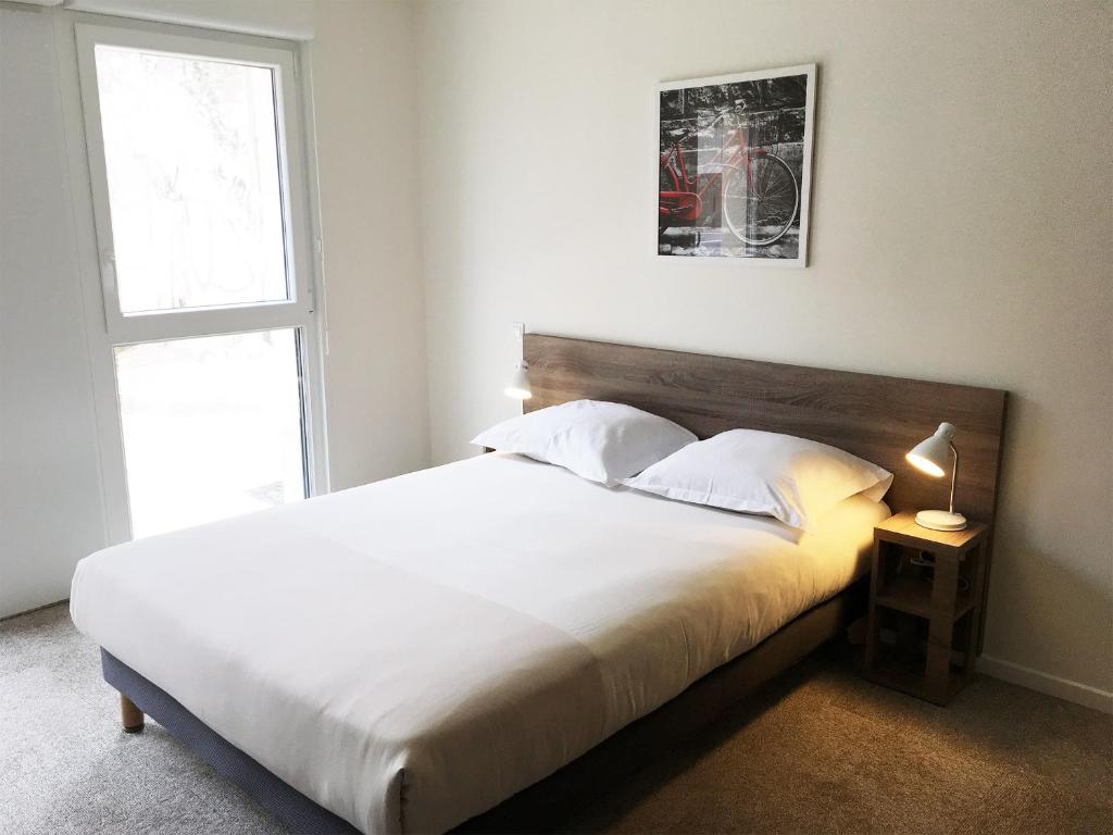 a bedroom with a large white bed with a window at Kosy Appart'hôtels Art'&Facts in Nancy