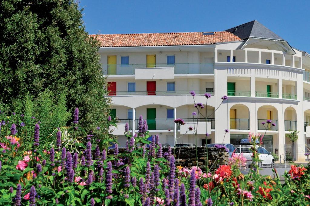 a large white building with colorful windows and flowers at Vacancéole - Les Jardins de l'Amirauté in Les Sables-d'Olonne