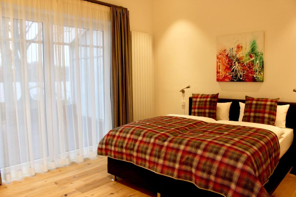a bedroom with a bed with a plaid blanket and a window at Hotel Seegarten in Barmstedt