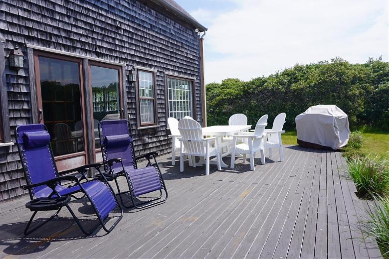 a deck with a table and chairs on a house at 9 Green Hollow Road in Nantucket