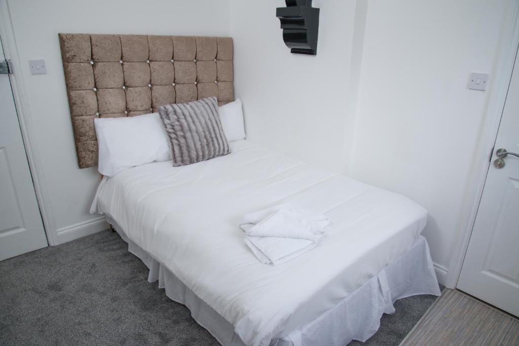 a bed with white sheets and a headboard in a room at TLK Apartments & Hotel - Beckenham in Beckenham