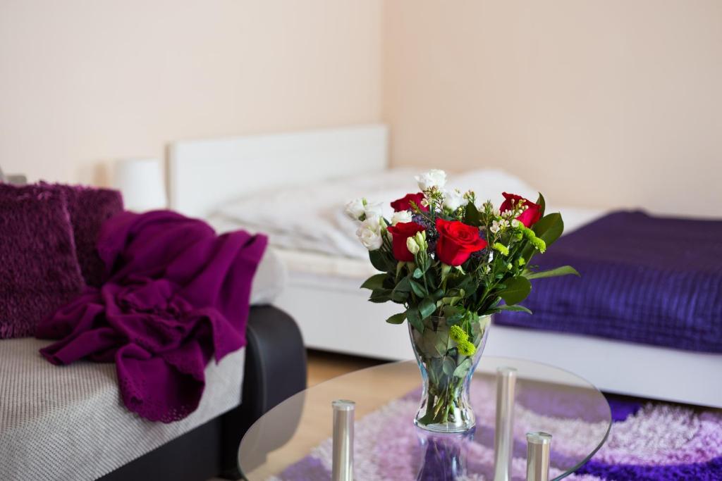 eine Vase mit Blumen auf einem Tisch in einem Schlafzimmer in der Unterkunft ApartHouse Apartamenty Centrum in Sosnowiec