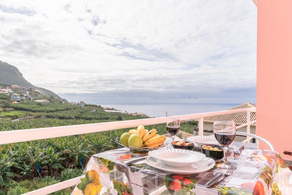 a table with food and wine glasses on a balcony at Casa Annie in Arco da Calheta