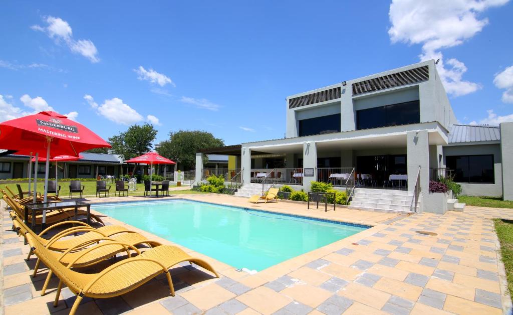 a pool with chairs and umbrellas in front of a building at Travelodge Kasane in Kasane