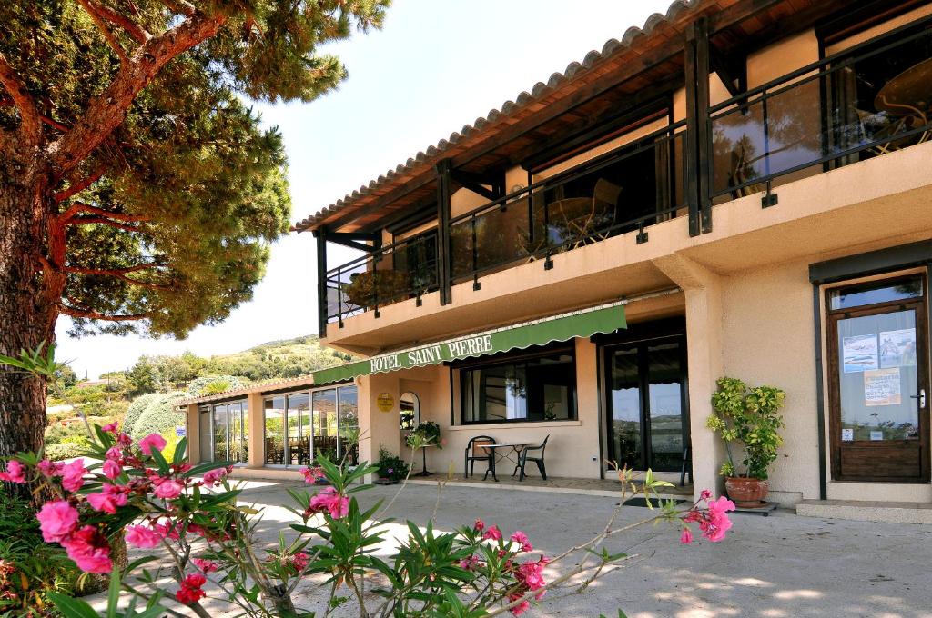 een gebouw met een balkon met roze bloemen bij Domaine de Saint Pierre in Cargèse