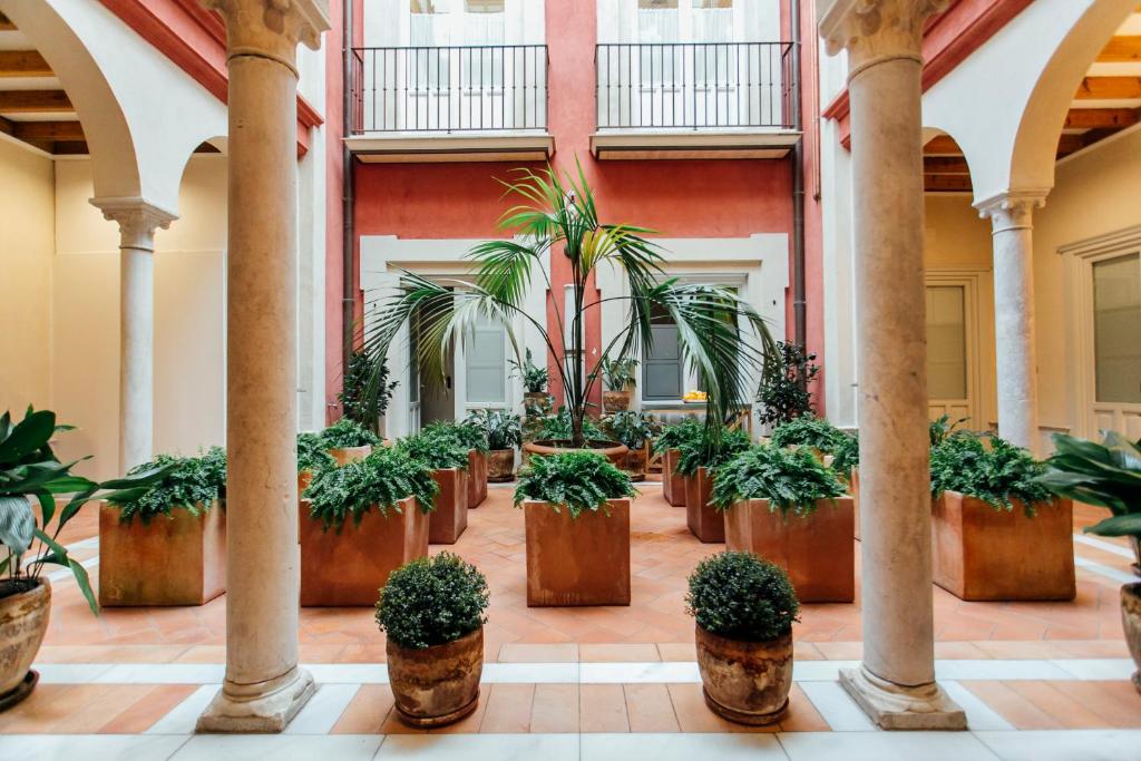 a lobby with potted plants and columns at Casa Patio del Siglo XIX in Seville