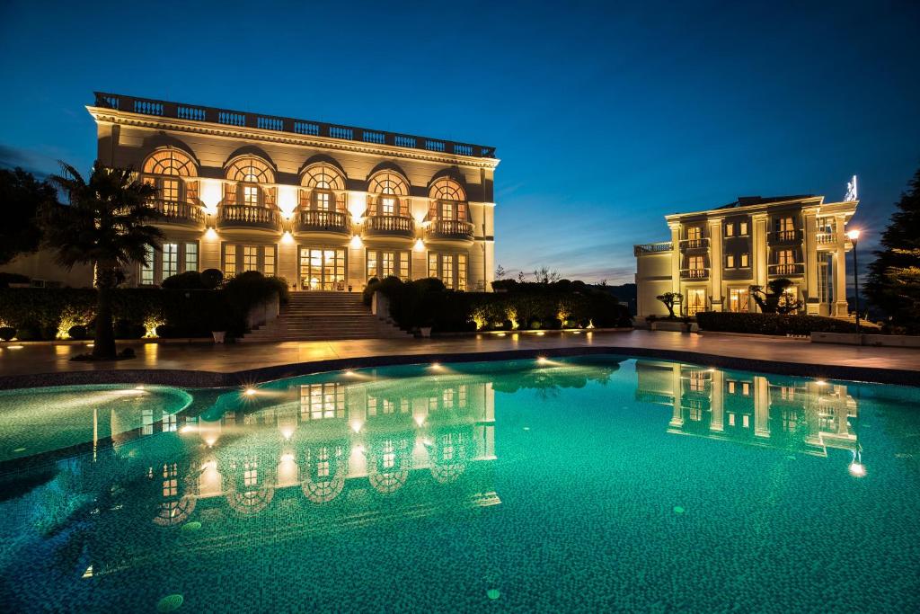a large building with a swimming pool at night at Royal Hill Hotel in Tirana