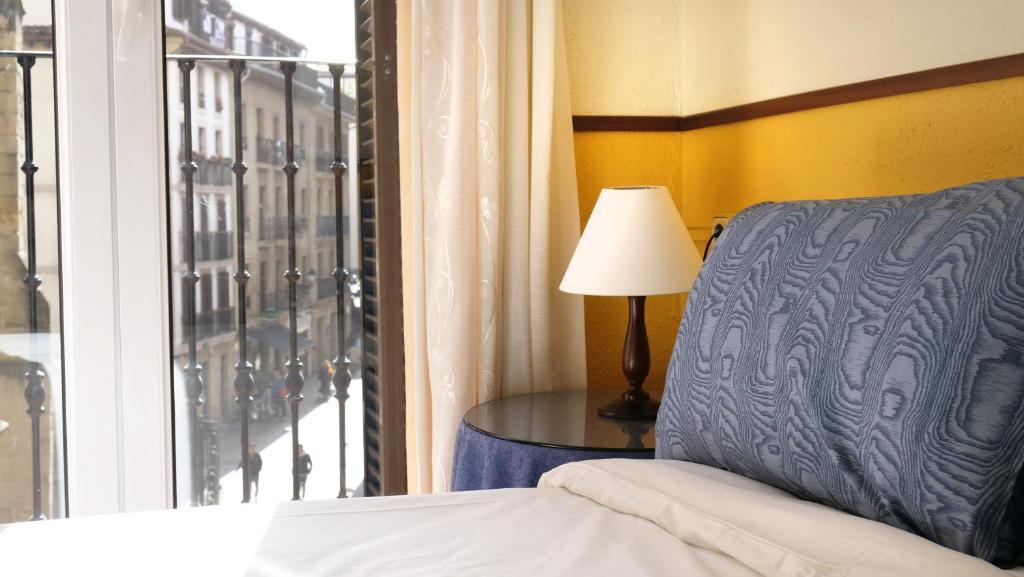 1 dormitorio con cama, lámpara y ventana en Apain HT en San Sebastián