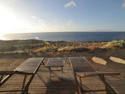 two benches and a picnic table on a deck overlooking the ocean at casa La Perdiz in Valverde