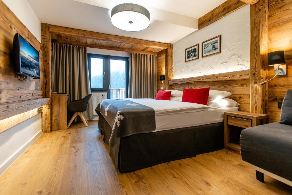 Cette chambre comprend un lit avec des oreillers rouges. dans l'établissement Hotel Olympie, à Špindlerův Mlýn