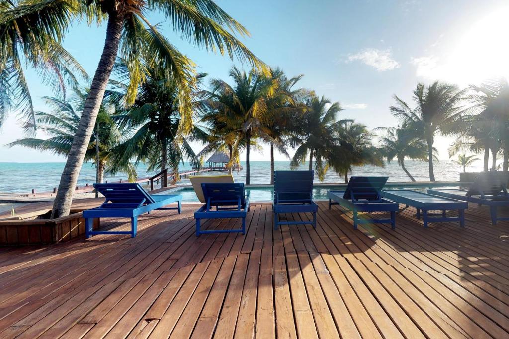 una terraza con sillas y mesas en la playa en Condo #27 @ Beachside Villas en Dangriga