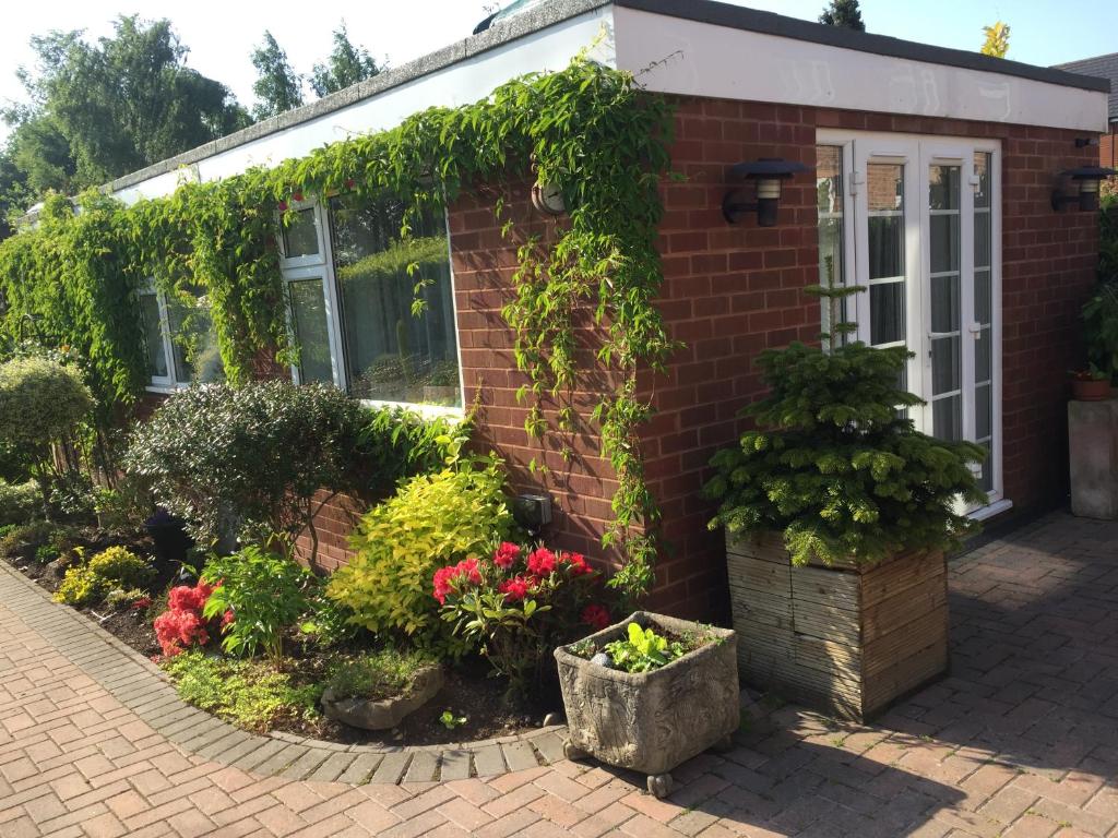ein Backsteinhaus mit Pflanzen und Blumen in der Unterkunft Cannock Chase Guest House Self Catering incl all home amenities & private entrance in Cannock