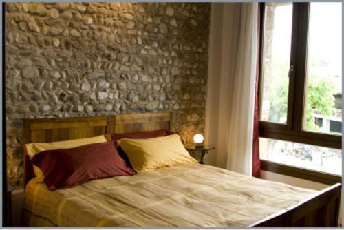 ein Bett in einem Schlafzimmer mit einer Steinmauer in der Unterkunft B&B Corte Alfier in Mortegliano