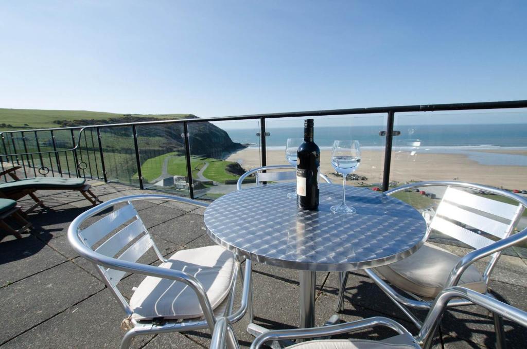 a table with a bottle of wine and two glasses at Clifton Court Apt 15 with Indoor Heated Pool in Croyde