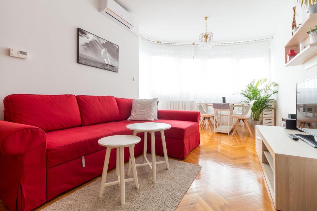 a living room with a red couch and two tables at "Apartment Zagreb Idila Center", with a balcony, speed WiFi in Zagreb