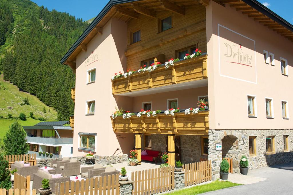 a building with a balcony with flowers on it at Pension Dorfplatzl in Sankt Leonhard im Pitztal