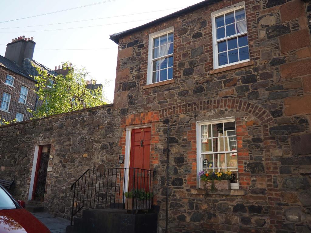 una casa de ladrillo con puerta roja y ventanas en No.33 Coach House, en Hillsborough