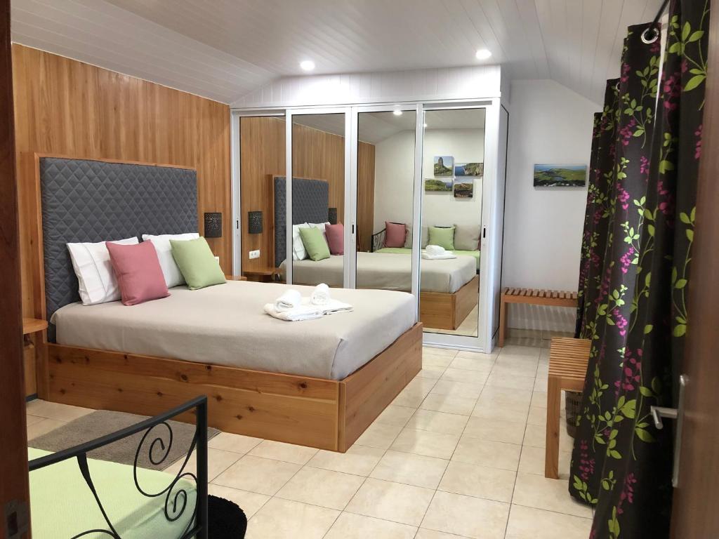a bedroom with a large bed and a mirror at Casa dos Morros in Lajes das Flores