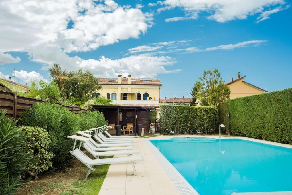 a swimming pool with lounge chairs next to a house at Villa con piscina a Rimini in Rimini