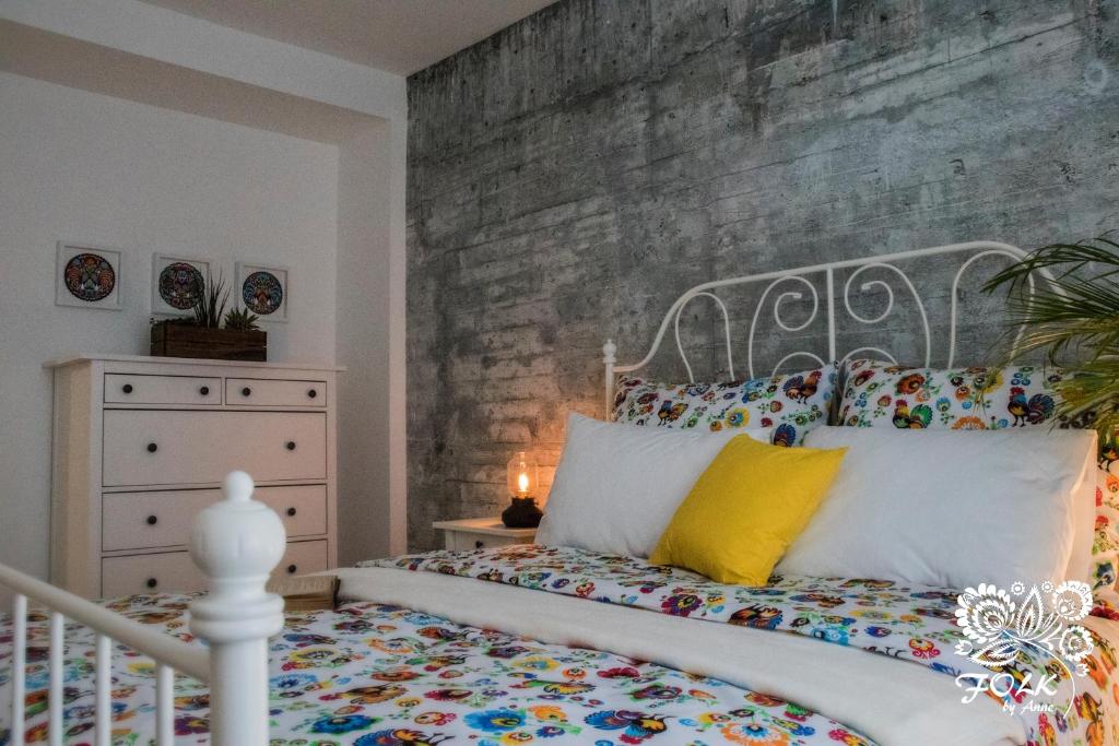 a bedroom with a bed and a painting on the wall at Folk by Anne Apartments & Rooms in Warsaw