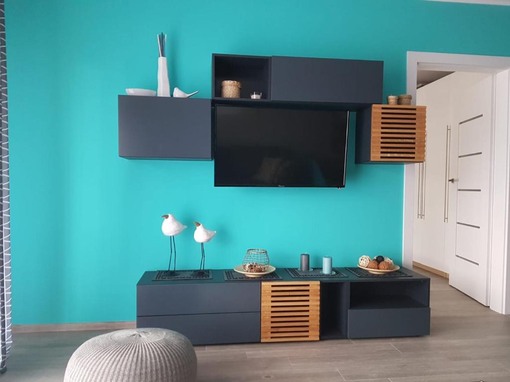salon z telewizorem na niebieskiej ścianie w obiekcie Morskie zacisze 22 w Pogorzelicy