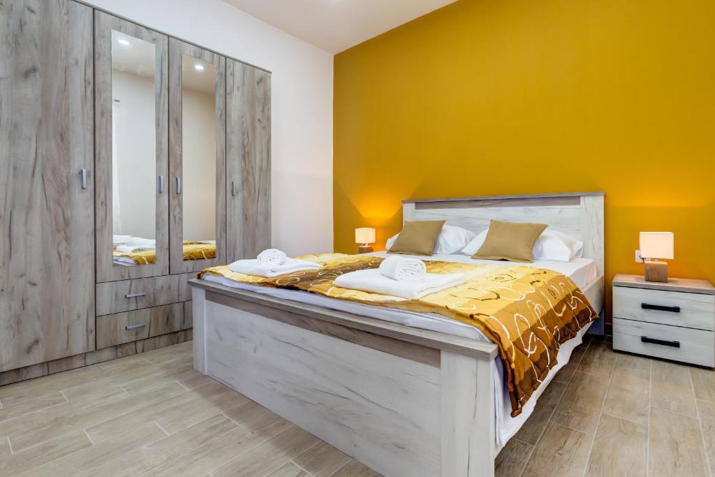 een slaapkamer met een groot bed met een gele muur bij Starfish Accommodation in Tivat