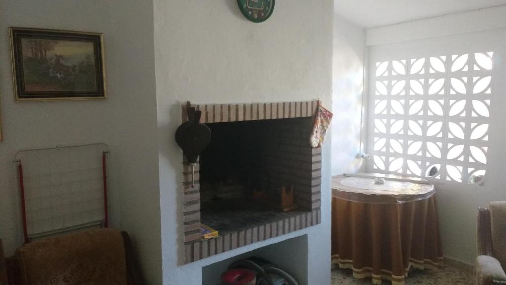 Una sala de estar con chimenea y una ventana. en Casa Fraile, en Olmedilla del Campo