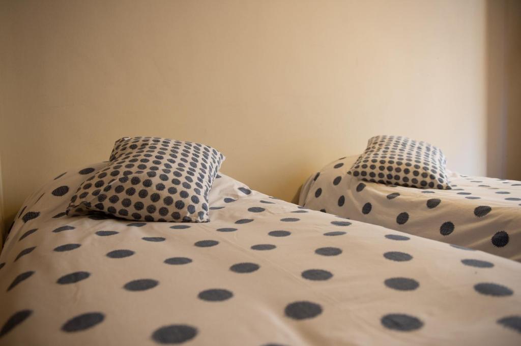 Duas camas com almofadas de bolinhas num quarto em Apartamentos Aguilar em Alcañiz
