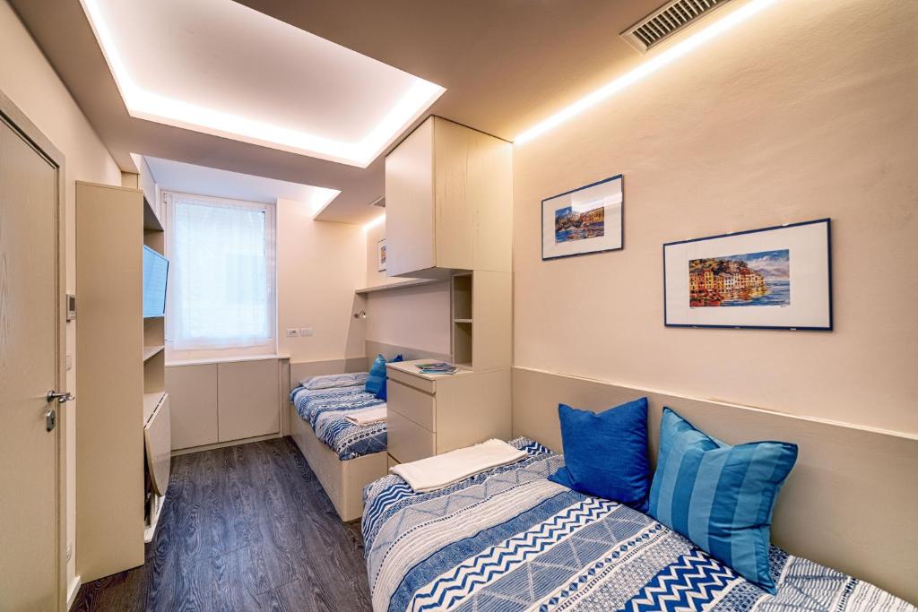 La Casetta di Portofino by PortofinoVip في بورتوفينو: سريرين في غرفة نوم مع وسائد زرقاء