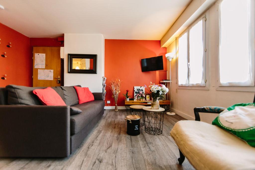 - un salon avec des murs orange et un canapé dans l'établissement Appartement de l'Eléphant, à Nantes