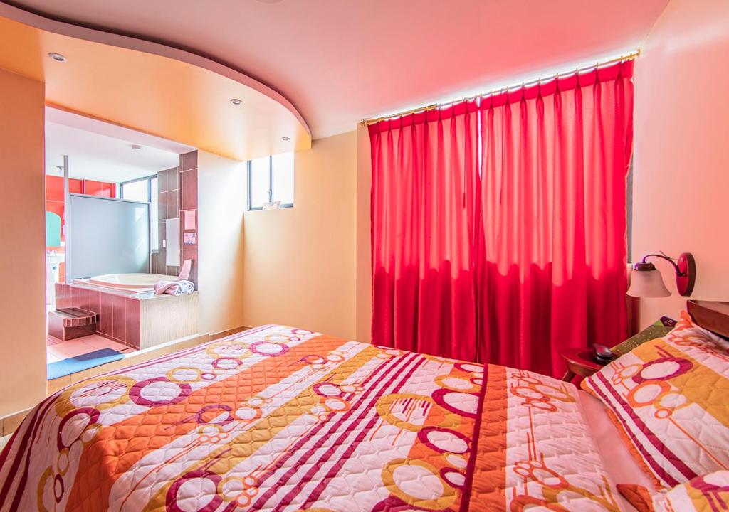 1 dormitorio con cama y cortina roja en Hostal Oro Orense, en Quito