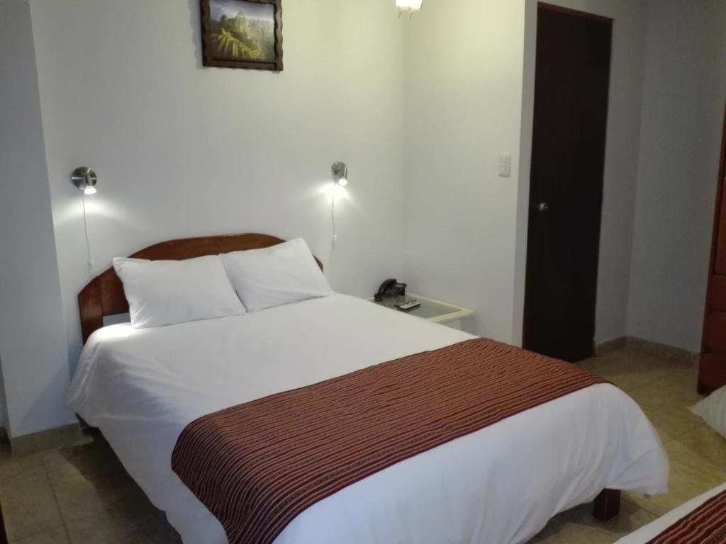 1 dormitorio con 1 cama blanca grande con manta marrón en MachuPicchu Dream, en Machu Picchu