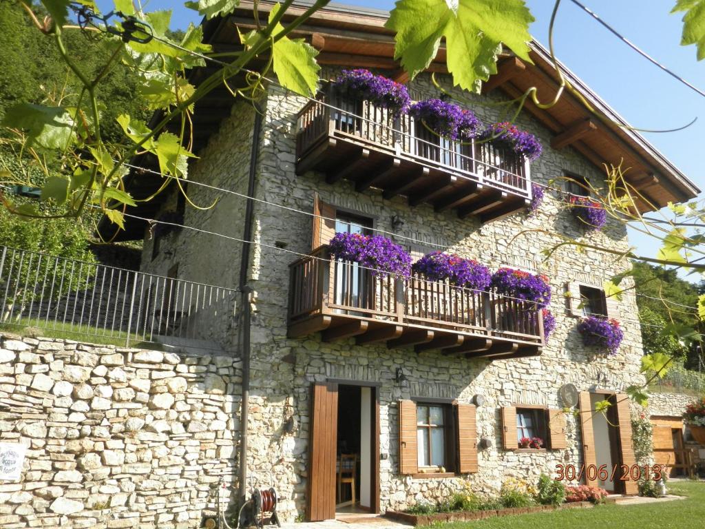 une maison en pierre avec des fleurs violettes sur les balcons dans l'établissement B&B Al Ghiro, à Villa Lagarina