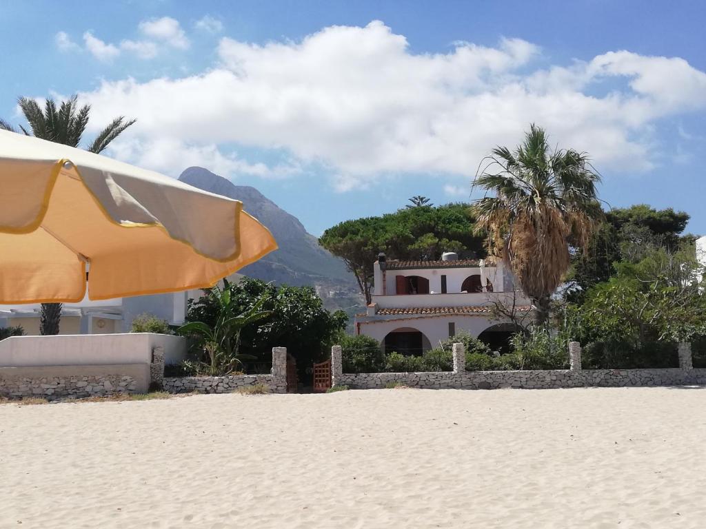 サン・ヴィート・ロ・カーポにあるVilla Hibiscoの傘を貸し切るビーチと背景の家